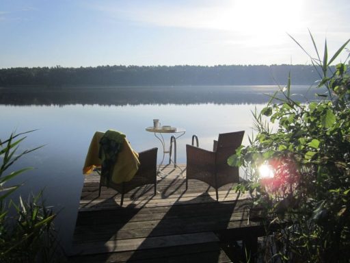 Schöne Szene am See mit zwei Stühlen und einem Tisch auf dem Steg am Ufer